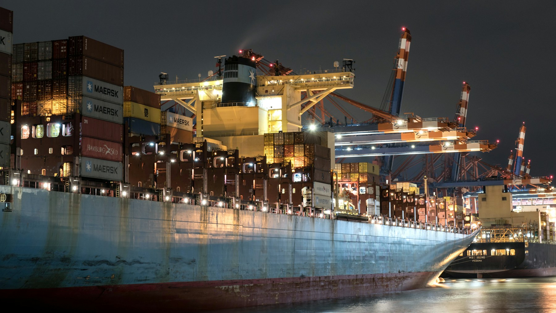Container ship and cargo cranes working at night